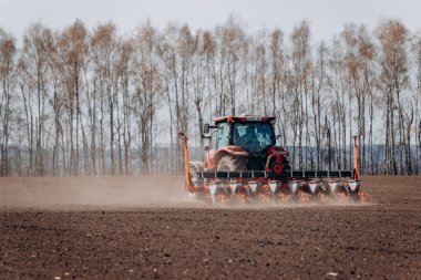 Vinnitsa, Ukrayna - 20 Nisan 2022: Bahar ekimi mevsimi. Traktörlü bir çiftçi tarlasına mısır tohumu ekiyor. İzli ekiciyle mısır ekiyorum. Çiftçilik tohumları