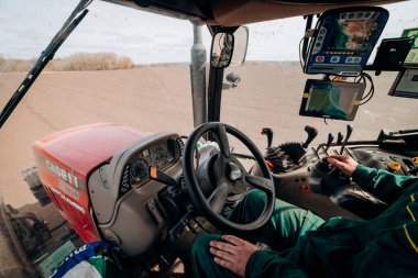 Vinnitsa, Ukraine - April 20, 2022: Spring sowing season. Farmer with a tractor sows corn seeds on his field. Planting corn with trailed planter. Farming seeding