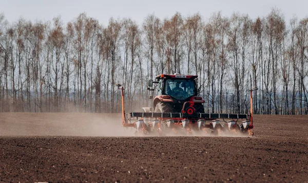 Vinnitsa, Ukrayna - 20 Nisan 2022: Bahar ekimi mevsimi. Traktörlü bir çiftçi tarlasına mısır tohumu ekiyor. İzli ekiciyle mısır ekiyorum. Çiftçilik tohumları