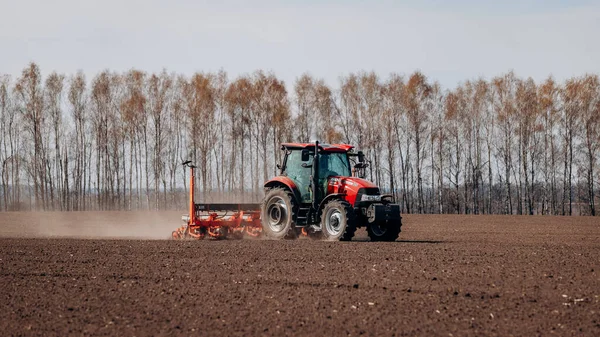 Vinnitsa, Ukrayna - 20 Nisan 2022: Bahar ekimi mevsimi. Traktörlü bir çiftçi tarlasına mısır tohumu ekiyor. İzli ekiciyle mısır ekiyorum. Çiftçilik tohumları