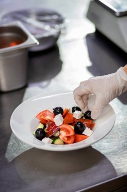 Taze hazırlanmış Yunan salatasını beyaz tabakta tutuyor. Vejetaryen salatası arayışı.