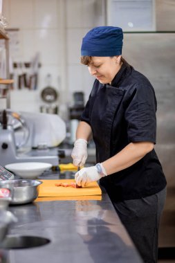 Mutfakta şef bir salatalık keser ve bir Yunan salatası hazırlar. Vejetaryen salatası arayışı.