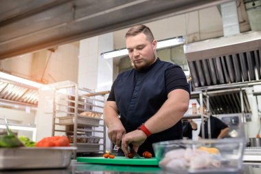 Mutfaktaki şef tavuk yemeği için domates kesiyor.