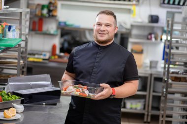 Şef içinde marine edilmiş tavuk olan bir yemek tabağı tutuyor.