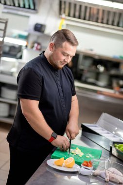 Mutfaktaki şef tavuk yemeği hazırlamak için taze soğan kesiyor.