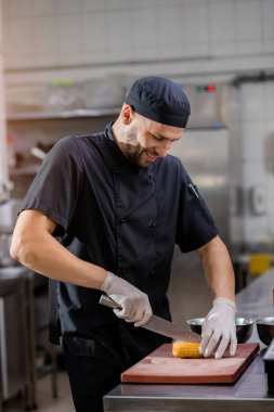 Şef ızgara yapmak için mutfak tahtasıyla bir mısır kamışı kesiyor.