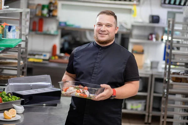 Şef içinde marine edilmiş tavuk olan bir yemek tabağı tutuyor.