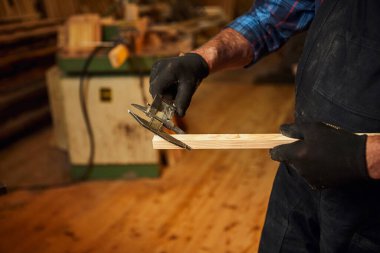 Marangozluk atölyesinde Caliper ile çalışan kıdemli profesyonel marangoz. Kapat.