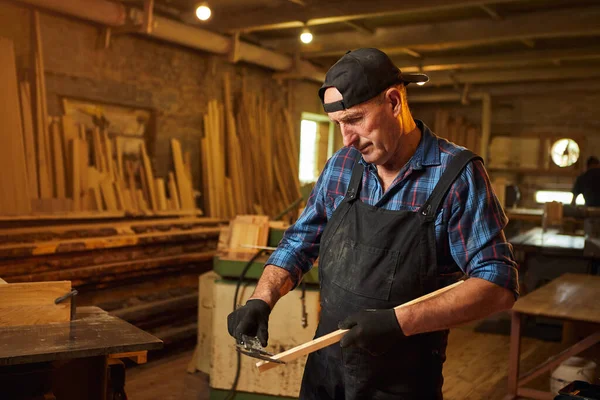 Marangozluk atölyesinde Caliper ile çalışan kıdemli profesyonel marangoz.