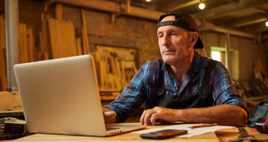 Kıdemli marangoz atölyedeki bilgisayarda çalışıyor.