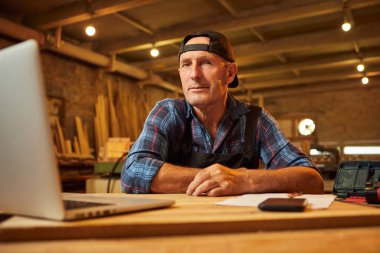 Gülümseyen marangoz portresi atölyedeki bilgisayarda çalışır.