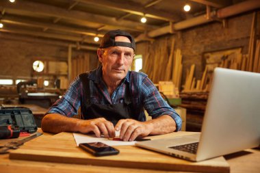 Gülümseyen marangoz portresi atölyedeki bilgisayarda çalışır.