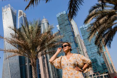 Dubai Marina bölgesinde uzun bir elbise giyen çekici bir gezgin kadın gezinti güvertesinde yürüyor. BAE 'de seyahat yerleri ve turist yaşam tarzı