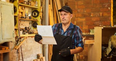 Üst düzey bir marangozun portresi marangozluk atölyesinde mobilya yapmayı planlıyor.