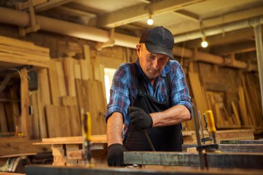 Üniformalı bir marangozun portresi marangozluk fabrikasında ahşap parmaklıkları el baskısıyla yapıştırıyor.