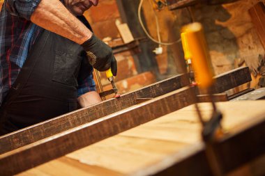 Üniformalı bir marangozun portresi marangozluk fabrikasında ahşap parmaklıkları el baskısıyla yapıştırıyor.