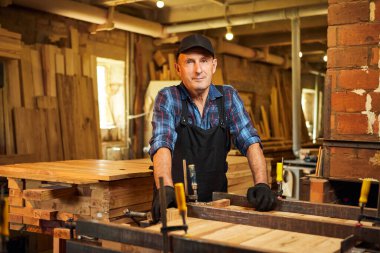 Üniformalı bir marangozun portresi marangozluk fabrikasında ahşap parmaklıkları el baskısıyla yapıştırıyor.