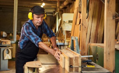 Üniformalı kıdemli marangoz marangozluk fabrikasında marangoz olarak çalışıyor.