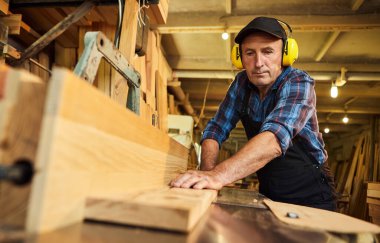 Üniformalı kıdemli marangoz marangozluk fabrikasında marangoz olarak çalışıyor.