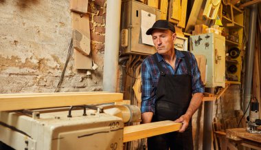 Üniformalı kıdemli marangoz marangozluk fabrikasında ahşap işçiliği yapıyor. 