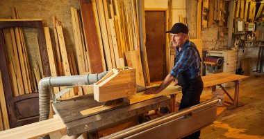 Elektrikli testere ile ahşap kesme masası. Kıdemli profesyonel marangoz üniformalı kereste fabrikasında ahşap tahta kesiyor. Testere makinesi