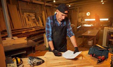 Üst düzey bir marangozun portresi marangozluk atölyesinde mobilya yapmayı planlıyor.