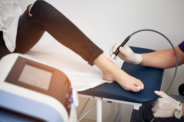 Ayak lazeri terapisi. Fizyoterapist doktor, çok etkili ayak ağrısı tedavisi için lazer tıbbi ekipman kullanıyor. Tıbbi ortopedik tedavi ve rehabilitasyon kavramı