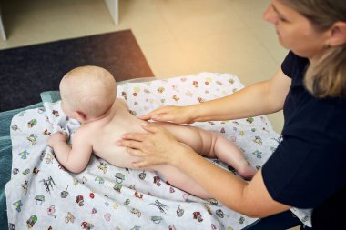 Masaj terapisti, tıp merkezinde şirin bir bebekle çalışıyor.