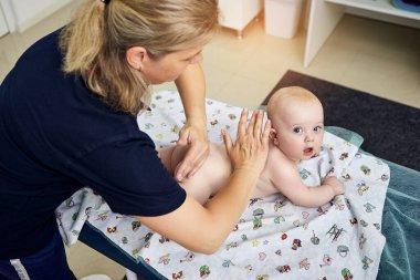 Masaj terapisti, tıp merkezinde şirin bir bebekle çalışıyor.
