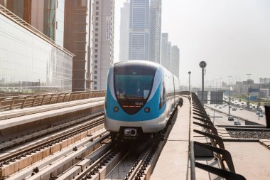 Dubai, Birleşik Arap Emirlikleri - 08 Kasım 2021: Dubai metro treni gökdelenlerin arka planında. Meşhur metro kırmızı hattı.