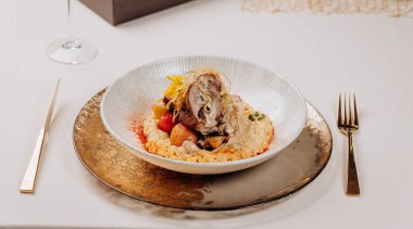 Restoranda sebze ve pirinç yastığında kuru erikli rulo et servis edilir.