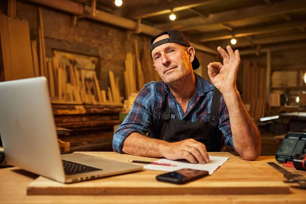 Gülümseyen marangozun portresi bilgisayarda çalışır ve atölyede imzayı gösterir.