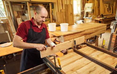 Üniformalı bir marangozun portresi marangozluk fabrikasında ahşap parmaklıkları el baskısıyla yapıştırıyor.