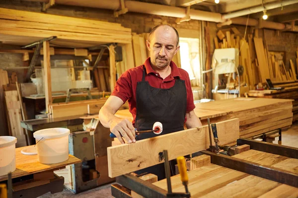 木匠制造业一名高级木匠穿着制服 用手压粘贴木棍的画像 — 图库照片