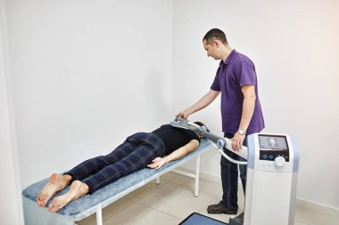 Sırtın elektromanyetik terapisi. Fizyoterapist doktor çok etkili ağrı tedavisi ve iltihap tedavisi için tıbbi ekipman kullanıyor. Manyetik alan, rehabilitasyon. Manyetoterapi