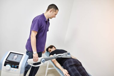 Sırtın elektromanyetik terapisi. Fizyoterapist doktor çok etkili ağrı tedavisi ve iltihap tedavisi için tıbbi ekipman kullanıyor. Manyetik alan, rehabilitasyon. Manyetoterapi