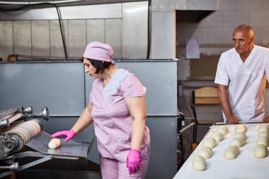 Fırıncı ekmek pişirmek için hamur oluşturur ve onu üretim tepsisine koyar.