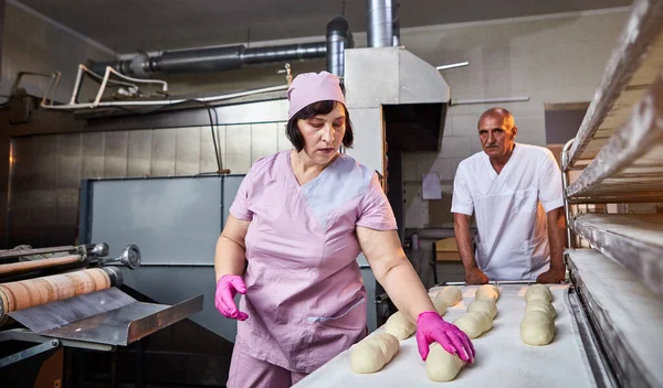 Fırıncı ekmek pişirmek için hamur oluşturur ve onu üretim tepsisine koyar.