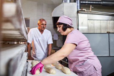 Fırıncı ekmek pişirmek için hamur oluşturur ve onu üretim tepsisine koyar.