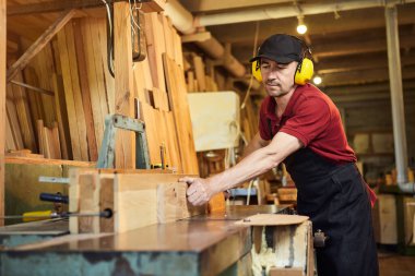 Üniformalı kıdemli marangoz marangozluk fabrikasında marangoz olarak çalışıyor.