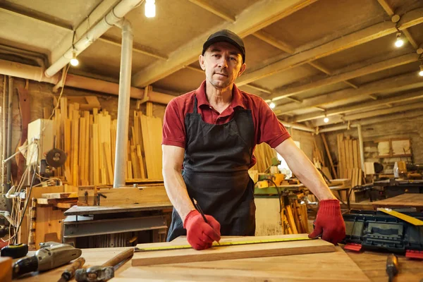 木匠用木头干活 用铅笔标出木板 测量木头的尺寸 在木工车间里做家具 — 图库照片