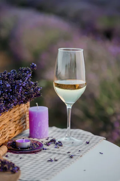 Glass of white wine in a lavender field in Provance. Violet flowers on the background