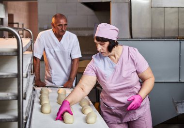 Fırıncı ekmek pişirmek için hamur oluşturur ve onu üretim tepsisine koyar.