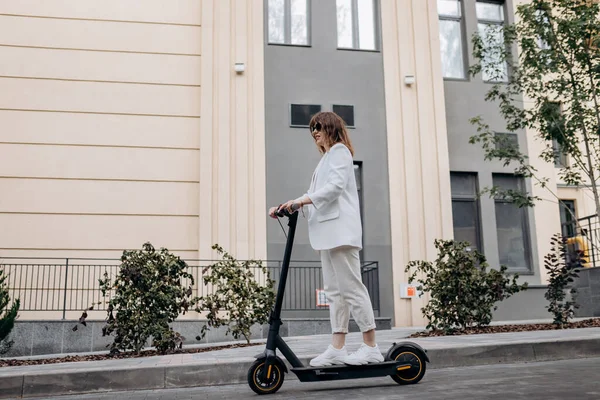 Beautiful Young Woman Sunglasses White Suit Riding Her Electric Scooter — Fotografia de Stock