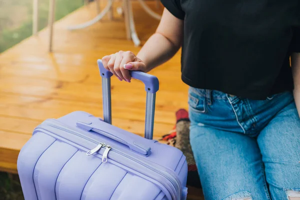 Close up of woman traveler with luggage sitting on background of cozy glamping house. Luxury camping tent for outdoor summer holiday and vacation. Lifestyle concept