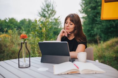Happy Woman freelancer using a laptop on a cozy glamping tent in a sunny day. Luxury camping tent for outdoor summer holiday and vacation. Lifestyle concept