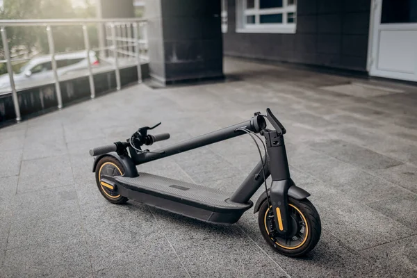Folded Electric scooter on concrete surface on urban street near modern building