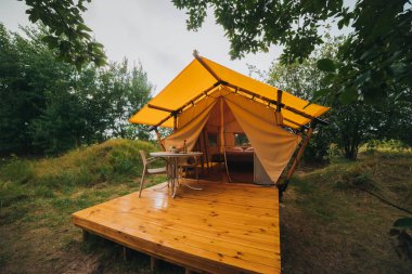 Gün batımında içinde ışık olan rahat, göz alıcı bir çadır. Yaz tatili ve tatil için lüks kamp çadırı. Yaşam tarzı kavramı