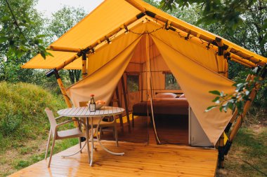 Gün batımında içinde ışık olan rahat, göz alıcı bir çadır. Yaz tatili ve tatil için lüks kamp çadırı. Yaşam tarzı kavramı