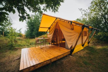 Gün batımında içinde ışık olan rahat, göz alıcı bir çadır. Yaz tatili ve tatil için lüks kamp çadırı. Yaşam tarzı kavramı